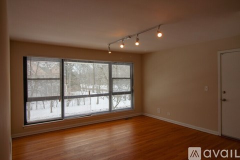A room with wooden floors and a large window overlooking a snowy landscape.