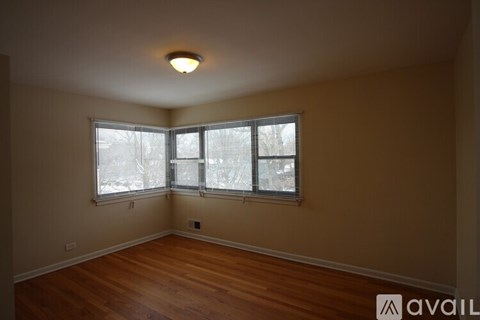 A room with wooden floors and a window with blinds.