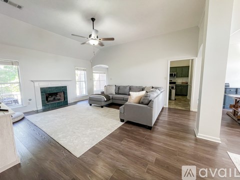 A spacious living room with a grey sofa and a fireplace.