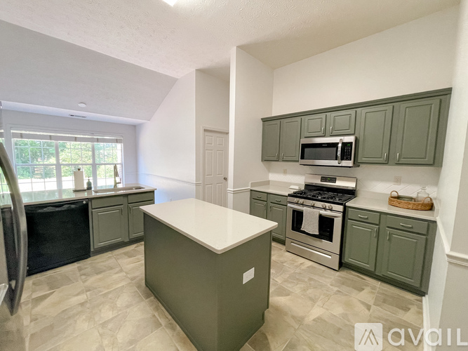 A kitchen with green cabinets and a white island.