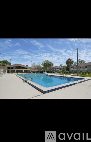 A pool surrounded by a white fence and a building in the background.