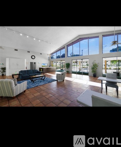 A spacious living room with a blue sofa and a large window overlooking a palm tree.