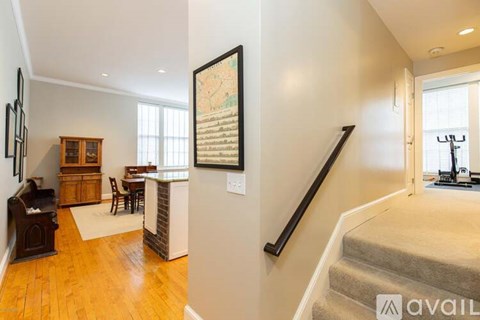 A living room with a couch, a chair, a table, a bookcase, and a painting on the wall.
