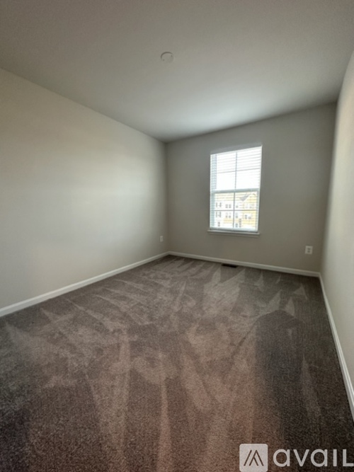 A room with a carpet and a window showing a building outside.