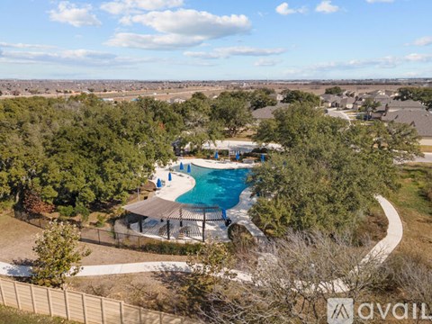 A pool surrounded by trees and a fence with the word "AVAIL" on it.