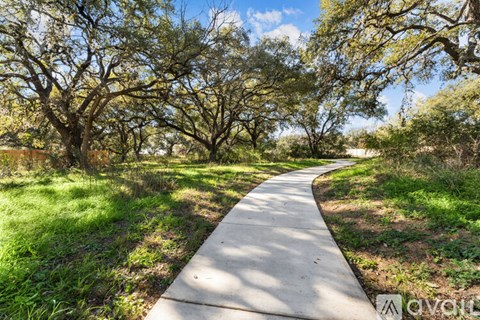 A concrete pathway leads through a grassy area with trees on either side.