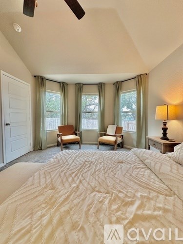 A bedroom with a large bed and two chairs.