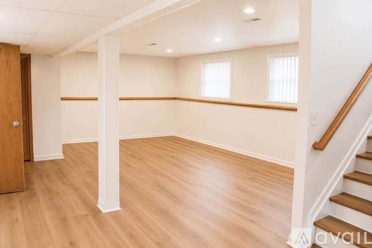 A spacious room with wooden floors and a staircase.