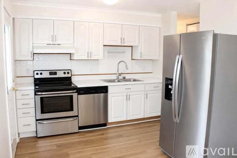 A kitchen with white cabinets and a stainless steel refrigerator.