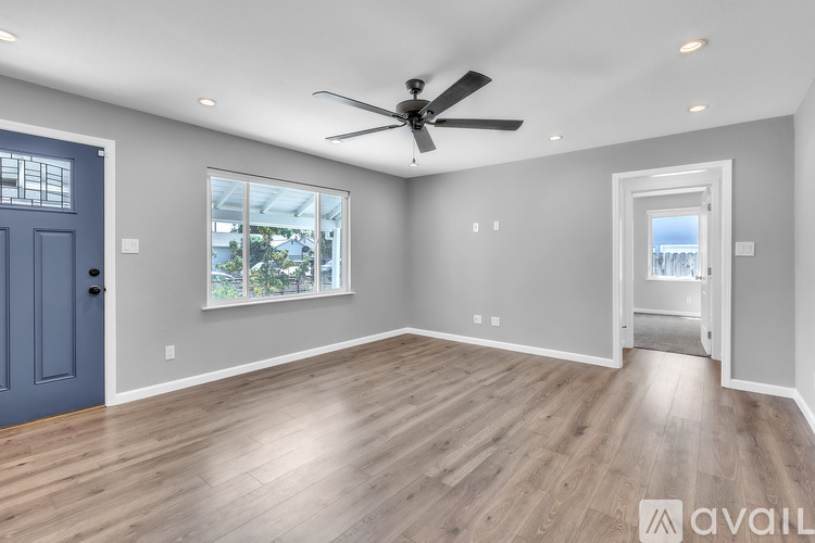 A spacious room with a ceiling fan and a view of the backyard through a window.
