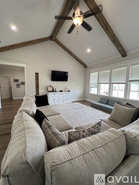 A living room with a large couch and a flat screen TV mounted on the wall.