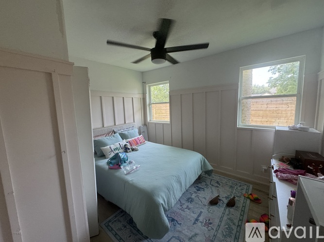 A bedroom with a bed, a ceiling fan, and a window.
