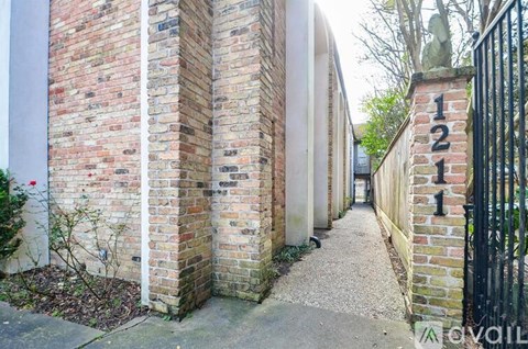 A narrow alley with brick walls and a black gate with the number 121 on it.