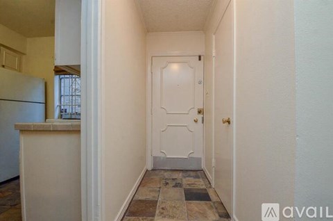 A hallway with a door and a tiled floor.
