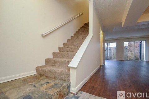 A staircase with a carpeted runner and a stone base leads to a large open space.