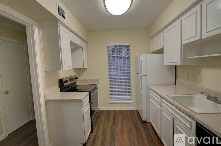 A kitchen with white cabinets and a window with blinds.