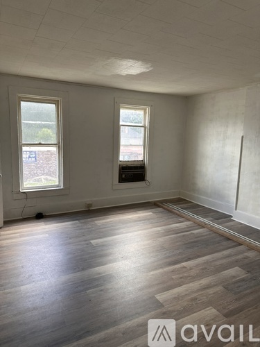 A room with wooden floors and two windows.