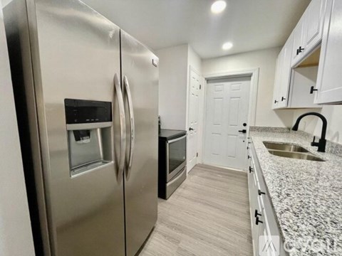 A modern kitchen with a stainless steel refrigerator and a granite countertop.