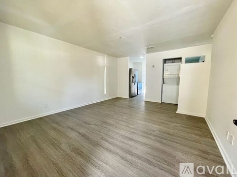 A spacious room with wooden flooring and white walls.
