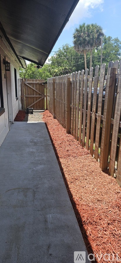 A wooden fence runs along the side of a concrete walkway.