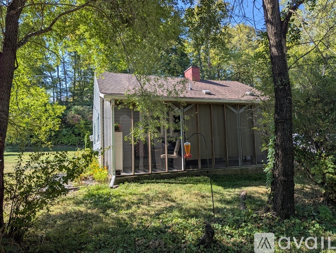 A small house with a porch surrounded by trees.