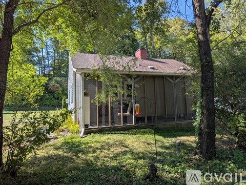 A small house with a porch surrounded by trees.