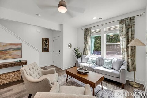 A living room with a grey couch, a wooden table, and a painting on the wall.