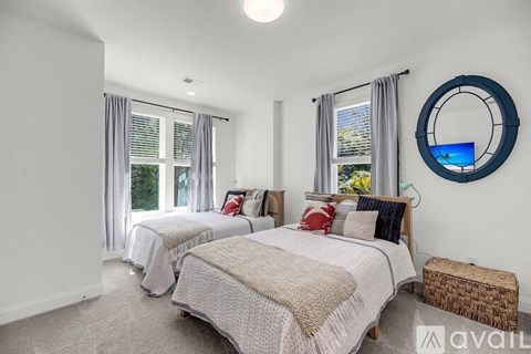 A bedroom with two beds and a round mirror on the wall.