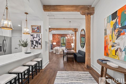 A modern living room with a bar area and a large painting on the wall.