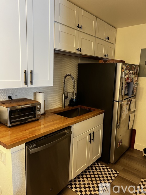 A kitchen with white cabinets and a black fridge.