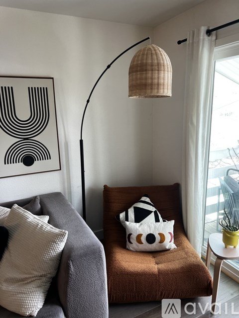 A living room with a grey couch, a lamp and a picture on the wall.