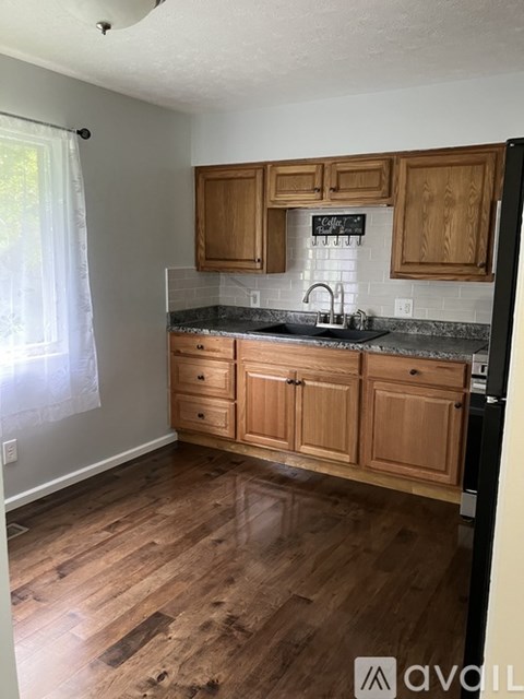 A kitchen with wooden cabinets and a black fridge.