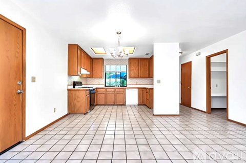 A kitchen with white tiled floors and wooden cabinets.