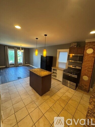 A kitchen with a brown island in the middle of a tiled floor.