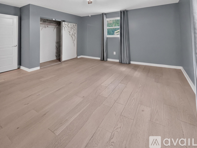A spacious room with wooden flooring and grey walls.