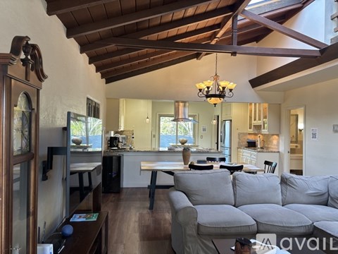 A living room with a grey couch and a wooden ceiling.