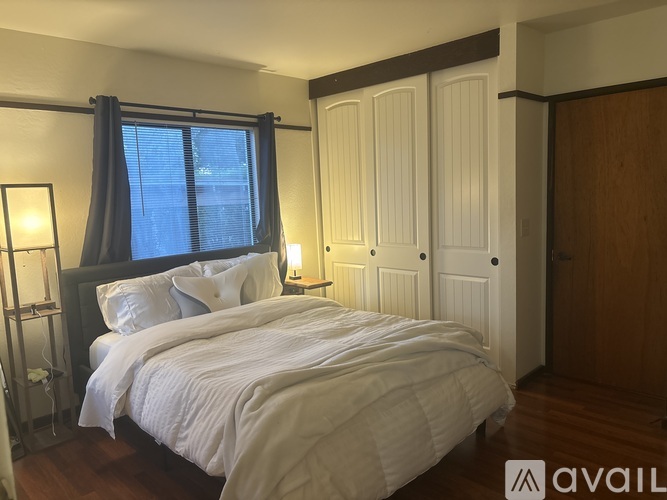 A bedroom with a large bed and a window with curtains.