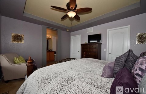 A bedroom with a large bed and a ceiling fan.