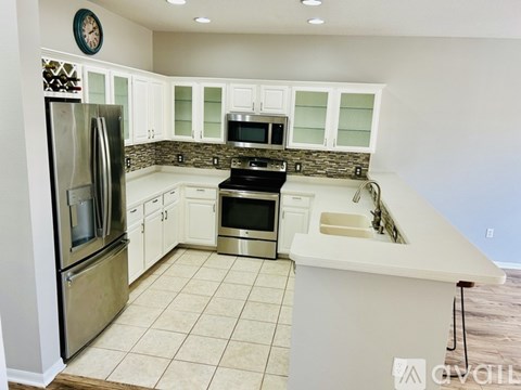A kitchen with white cabinets and a stainless steel refrigerator.