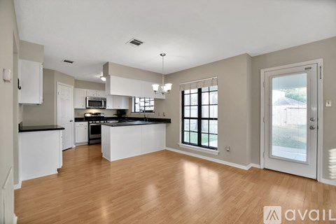 A kitchen with white cabinets and a black countertop.