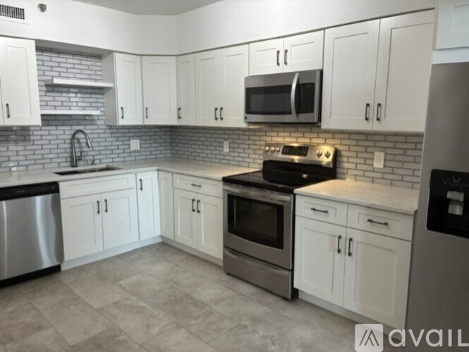 A kitchen with white cabinets and a brick backsplash.