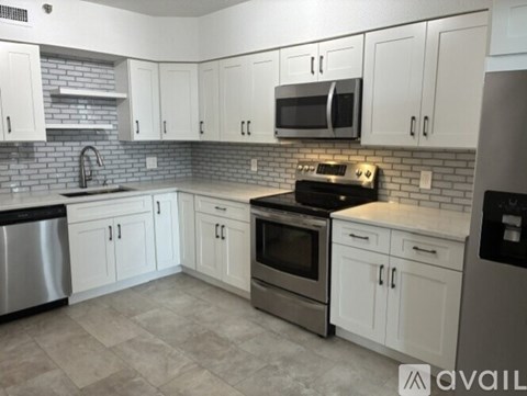 A kitchen with white cabinets and a brick backsplash.