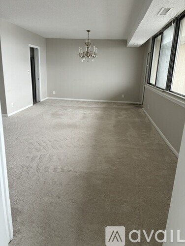 A spacious room with a chandelier and large windows.
