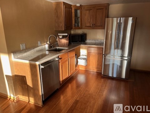 A kitchen with wooden cabinets and a stainless steel refrigerator.
