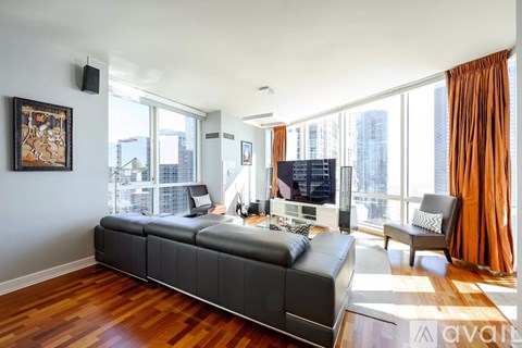 A living room with a black leather couch and a television.