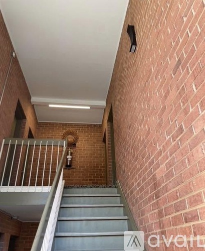 A staircase with a metal railing and a brick wall.