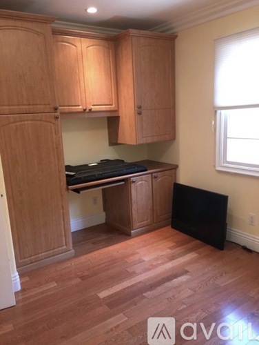 A kitchen with wooden cabinets and a black fridge.