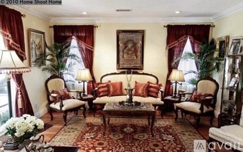 A living room with a large rug and a painting on the wall.