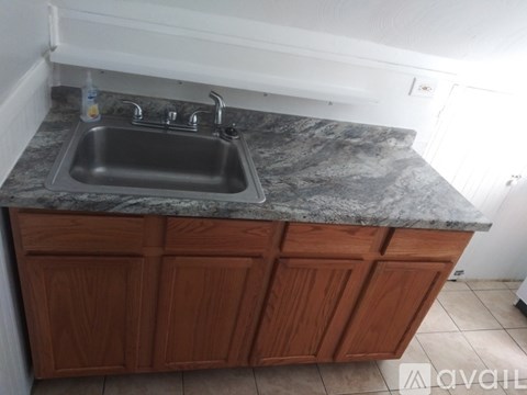 A kitchen sink with a granite countertop and wooden cabinets.