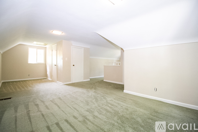 A spacious room with a carpeted floor and a window.